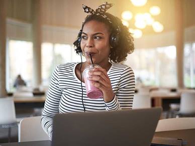 Woman drinking a smoothie whilst sat in front of her laptop